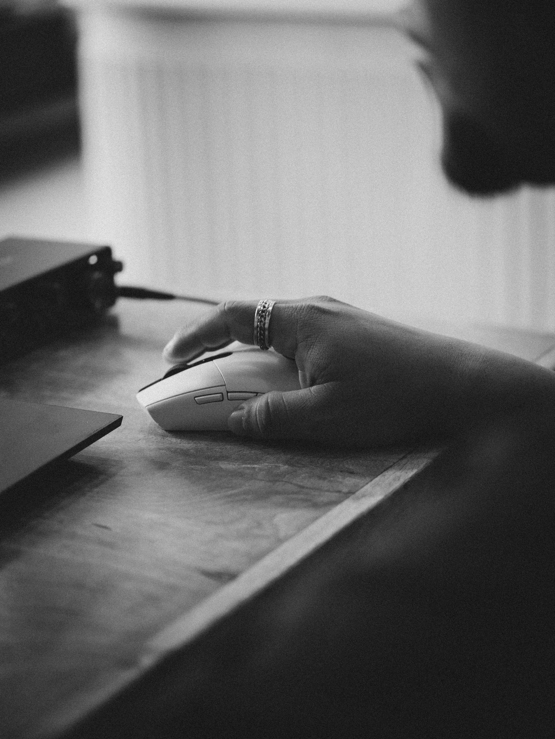 A hand poised over a page at an empty desk, black and white