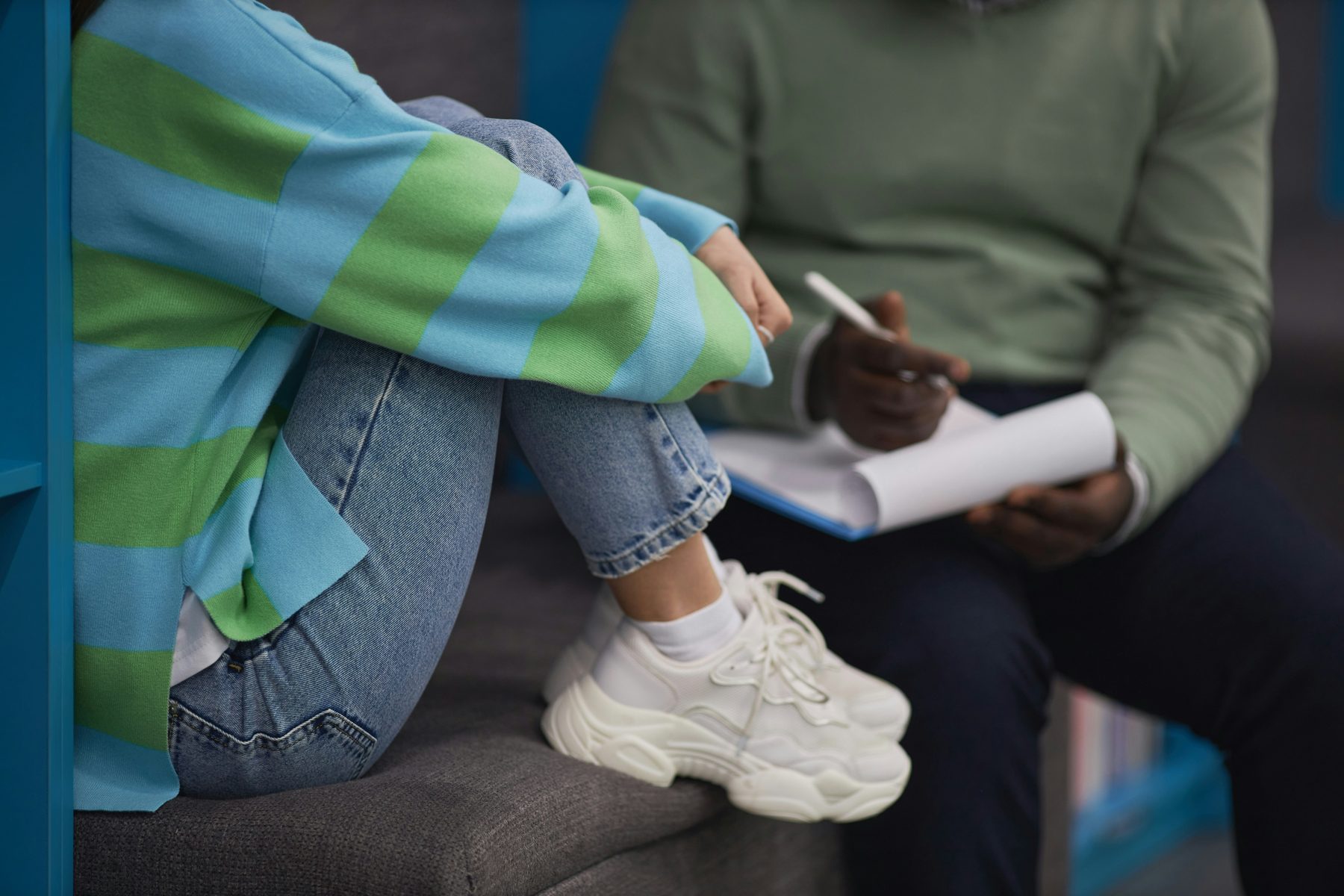 A teenager writing on a pad, trainers up on the seat