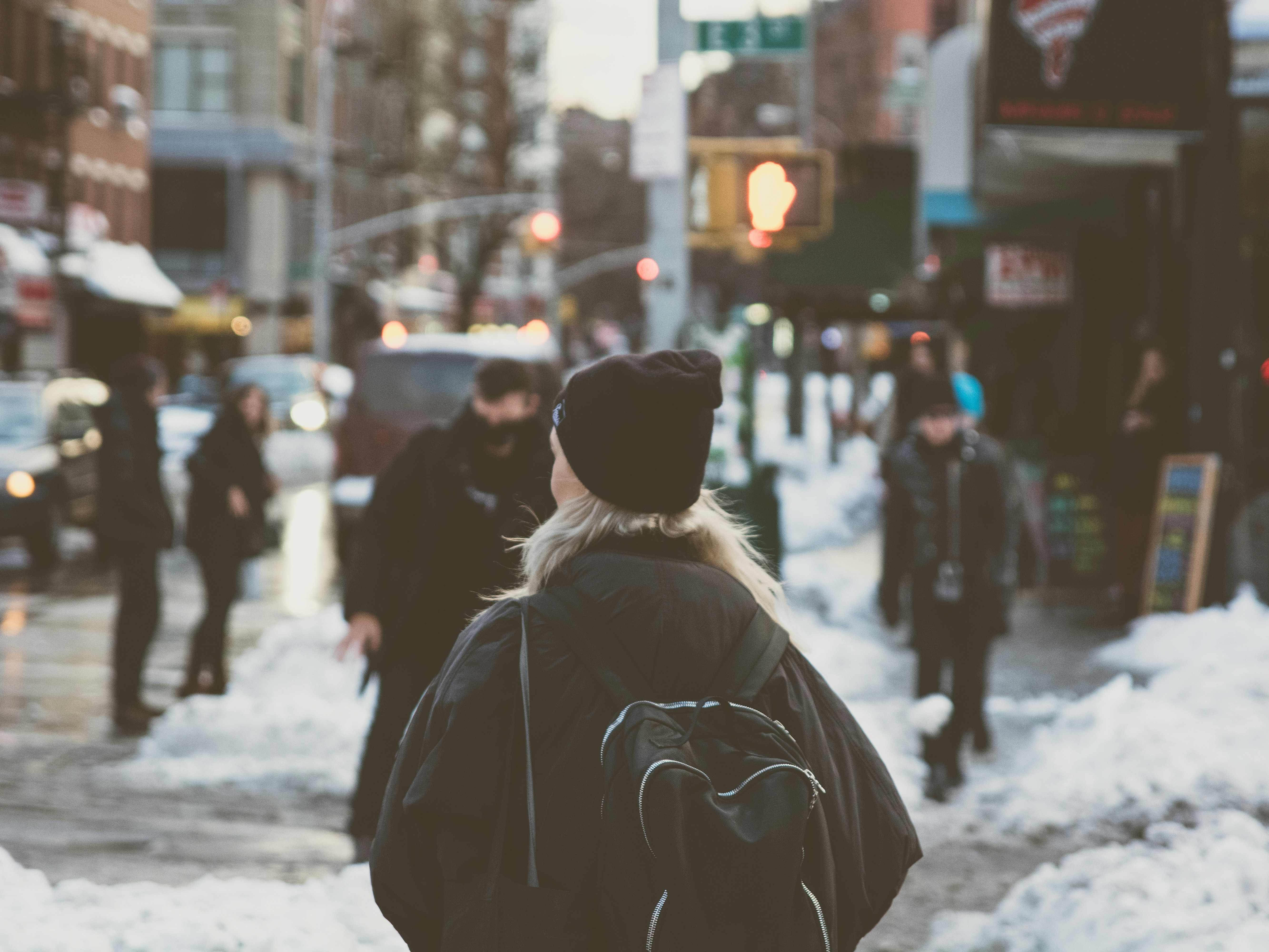 A person with a backpack moving through a crowded snowy street