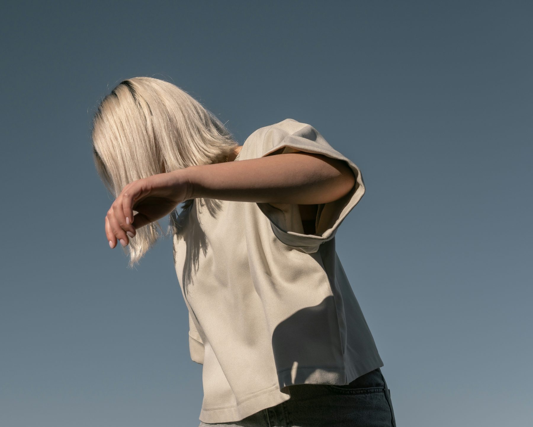 An adult shielding their face with an arm against the light, spent