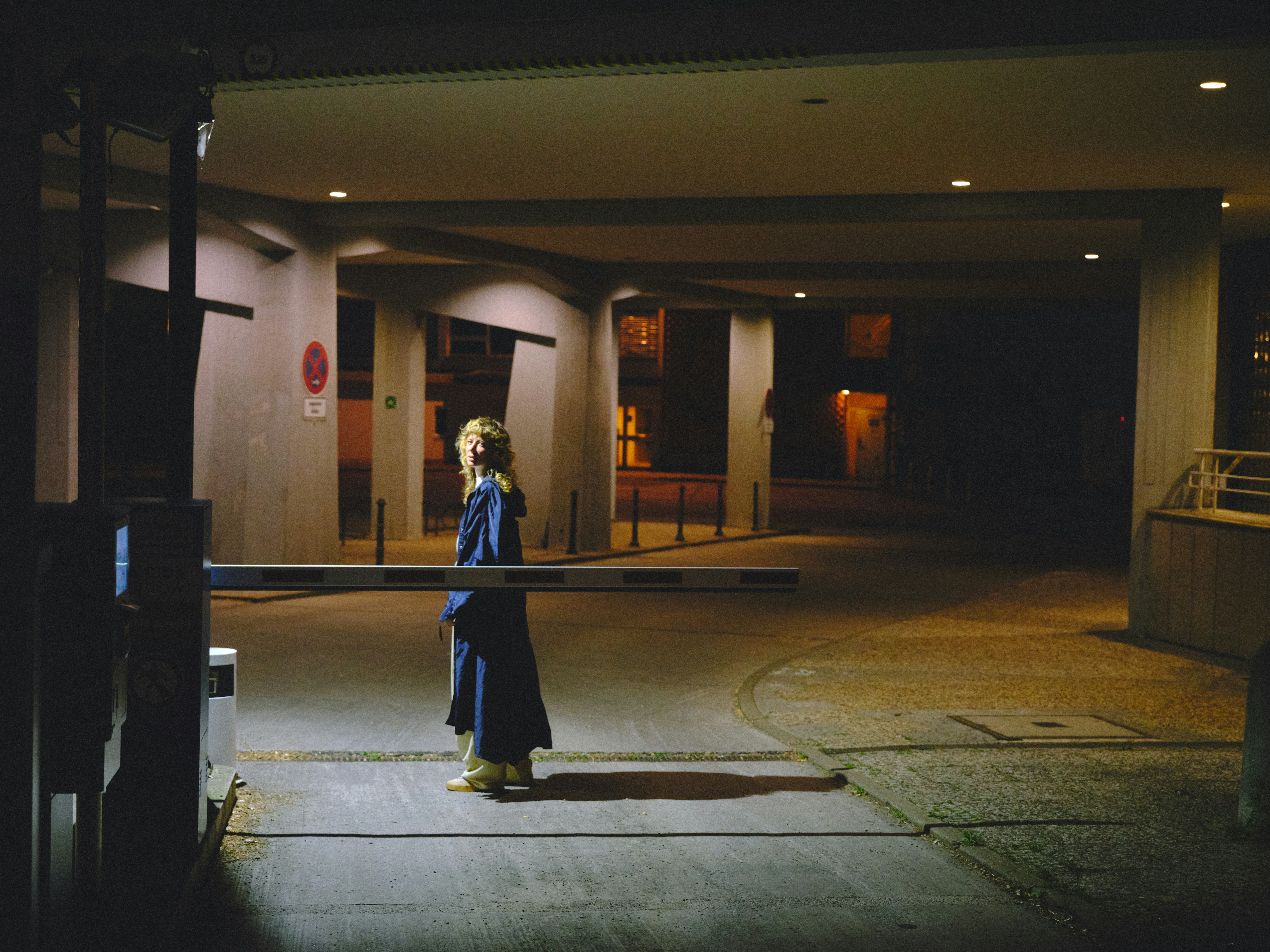 A lone figure standing in a dark parking garage