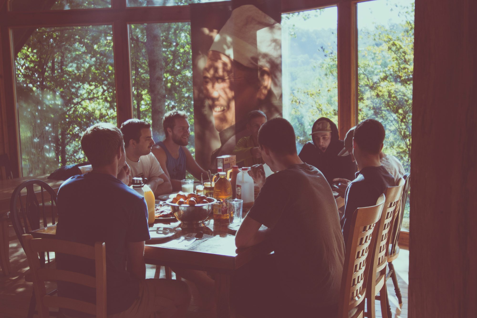 Friends gathered around a long table sharing a slow meal in daylight